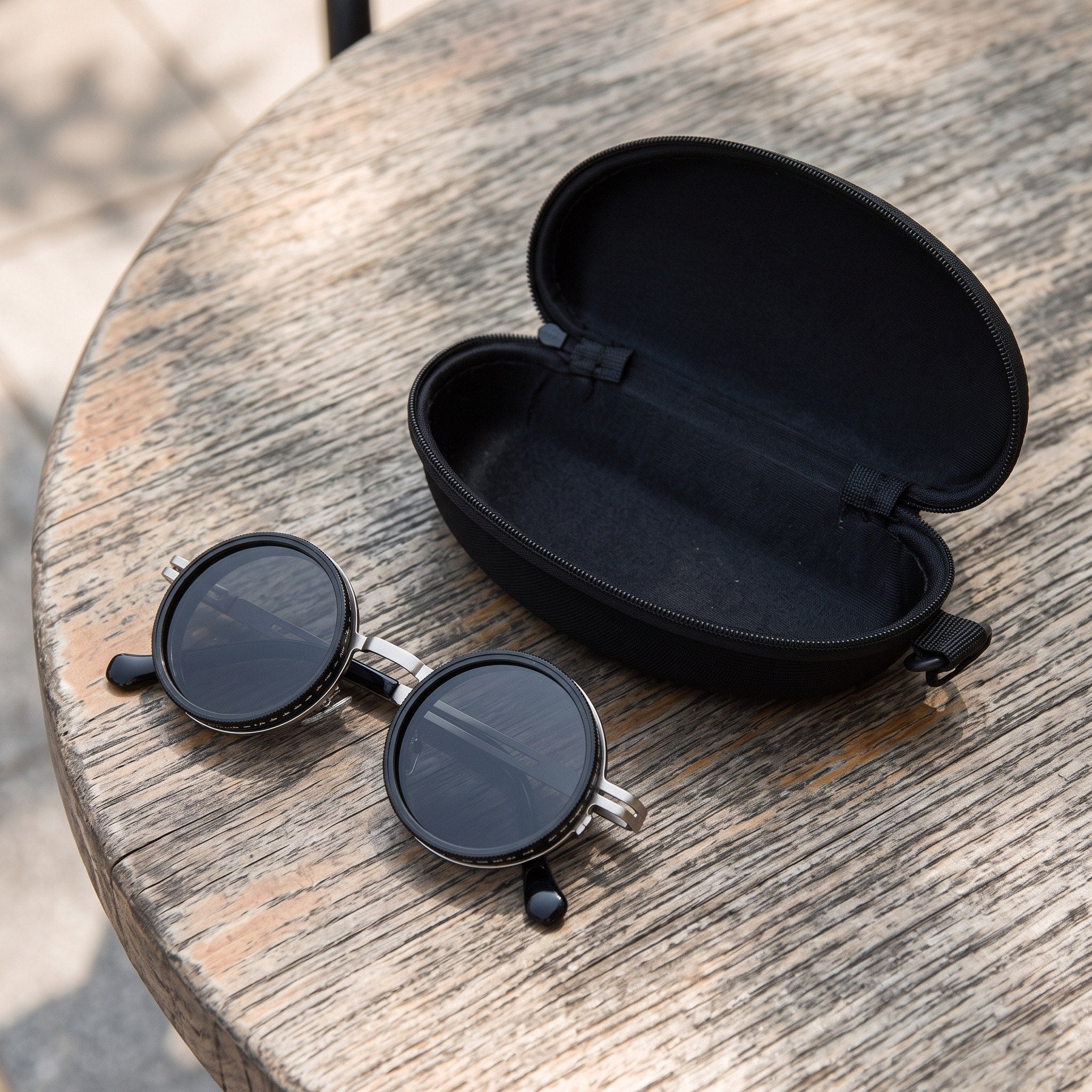 Silver sunglasses beside the included black zip case