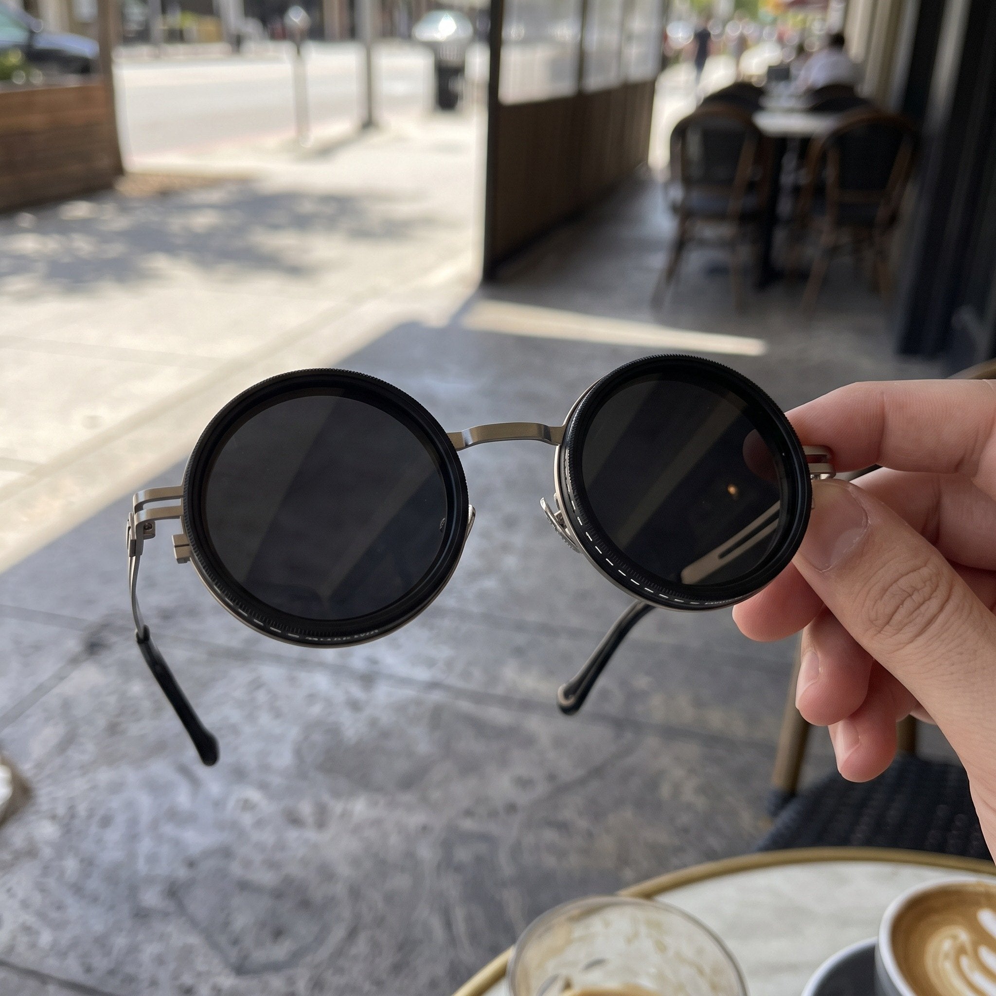 Silver sunglasses held outside a cafe