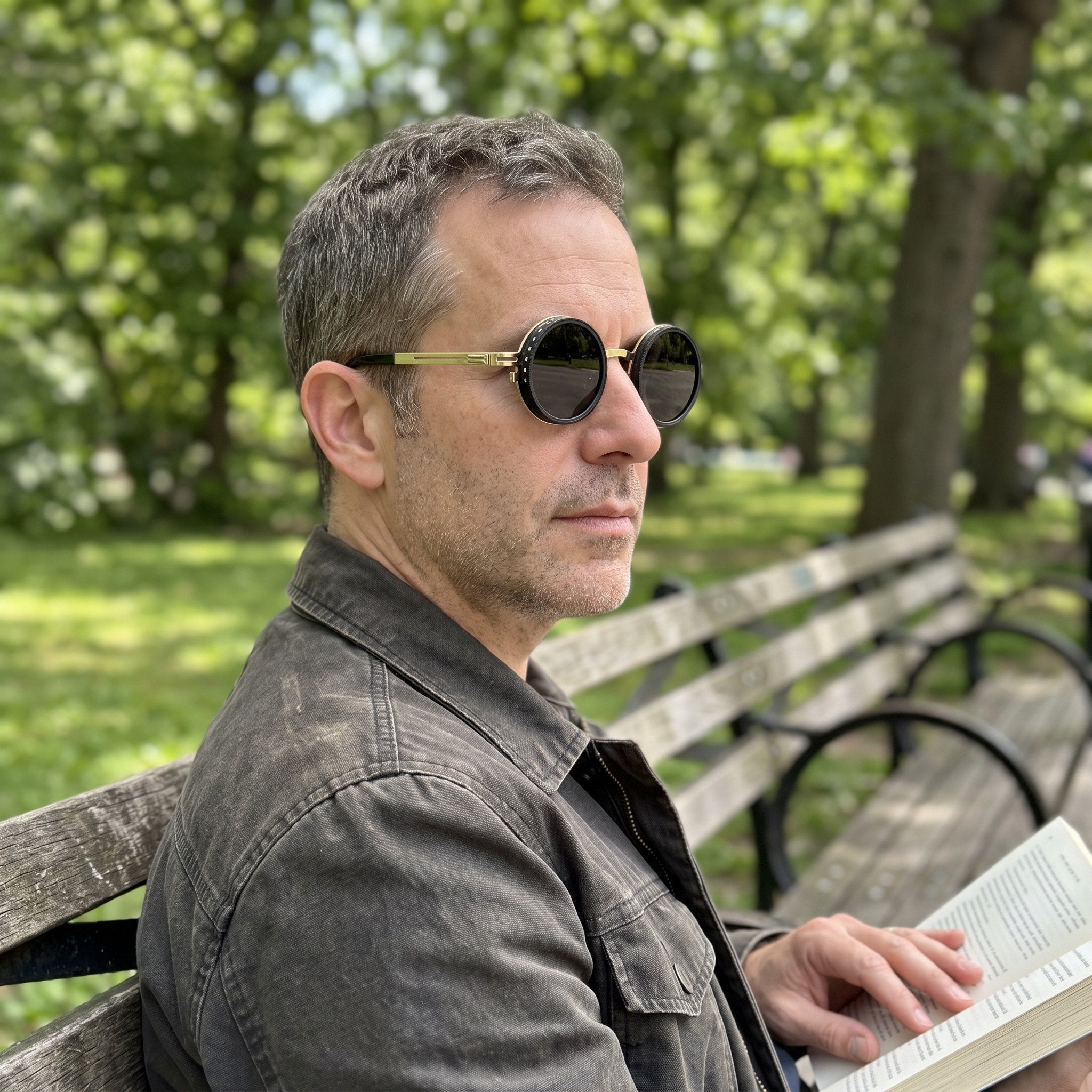 Gold sunglasses worn while reading on a park bench