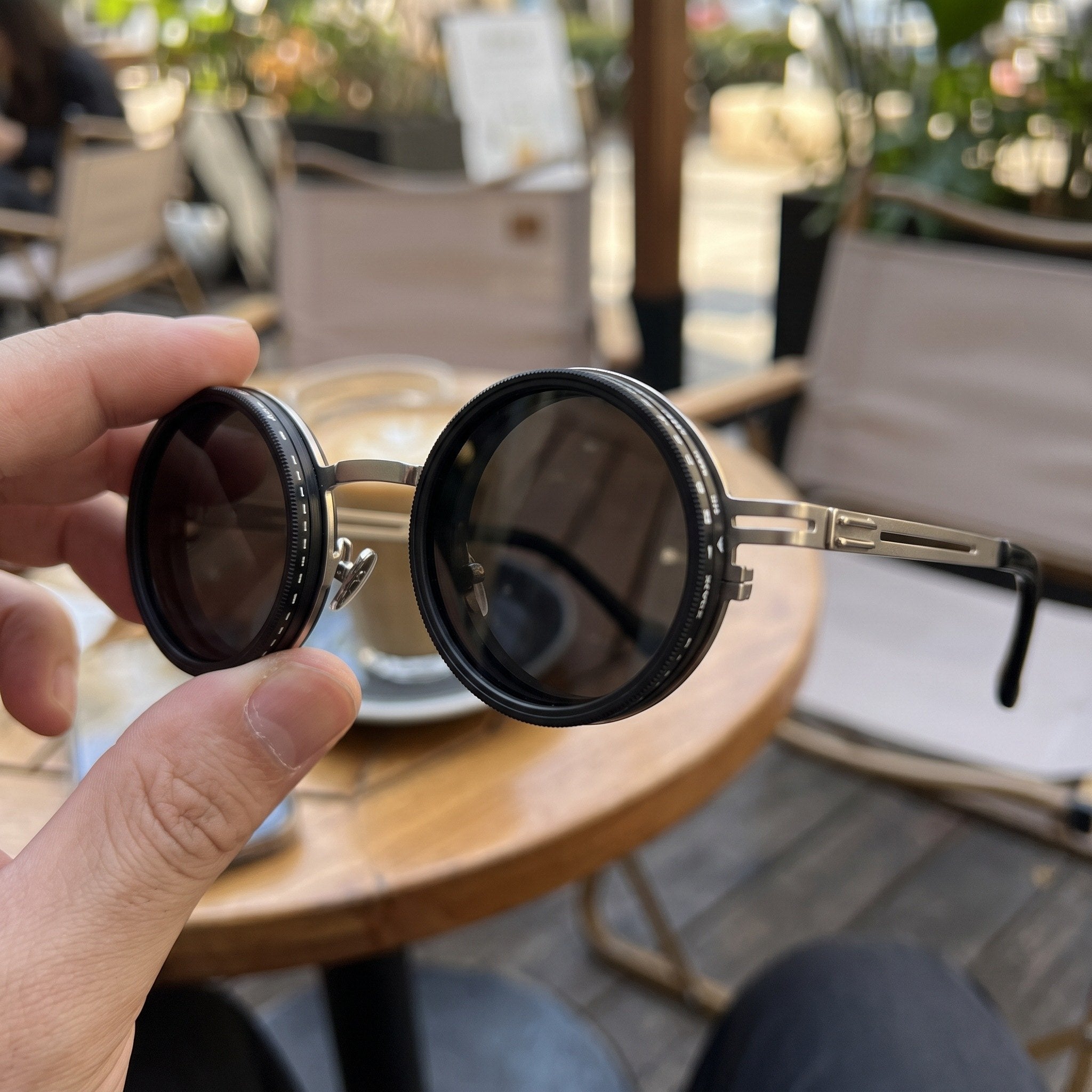 Silver sunglasses held near the frame hinge